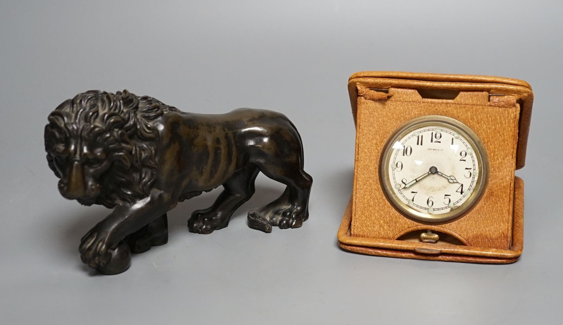 A bronze lion and Tiffany travelling watch, in tan leather case, lion 16.5 cms wide.